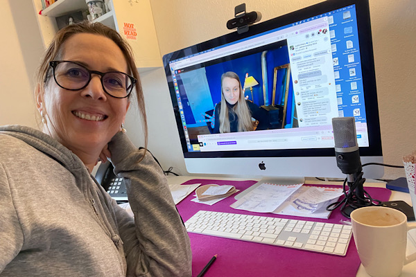 Lektorin Christine Storck sitzt vor ihrem Computer und lacht in die Kamera.