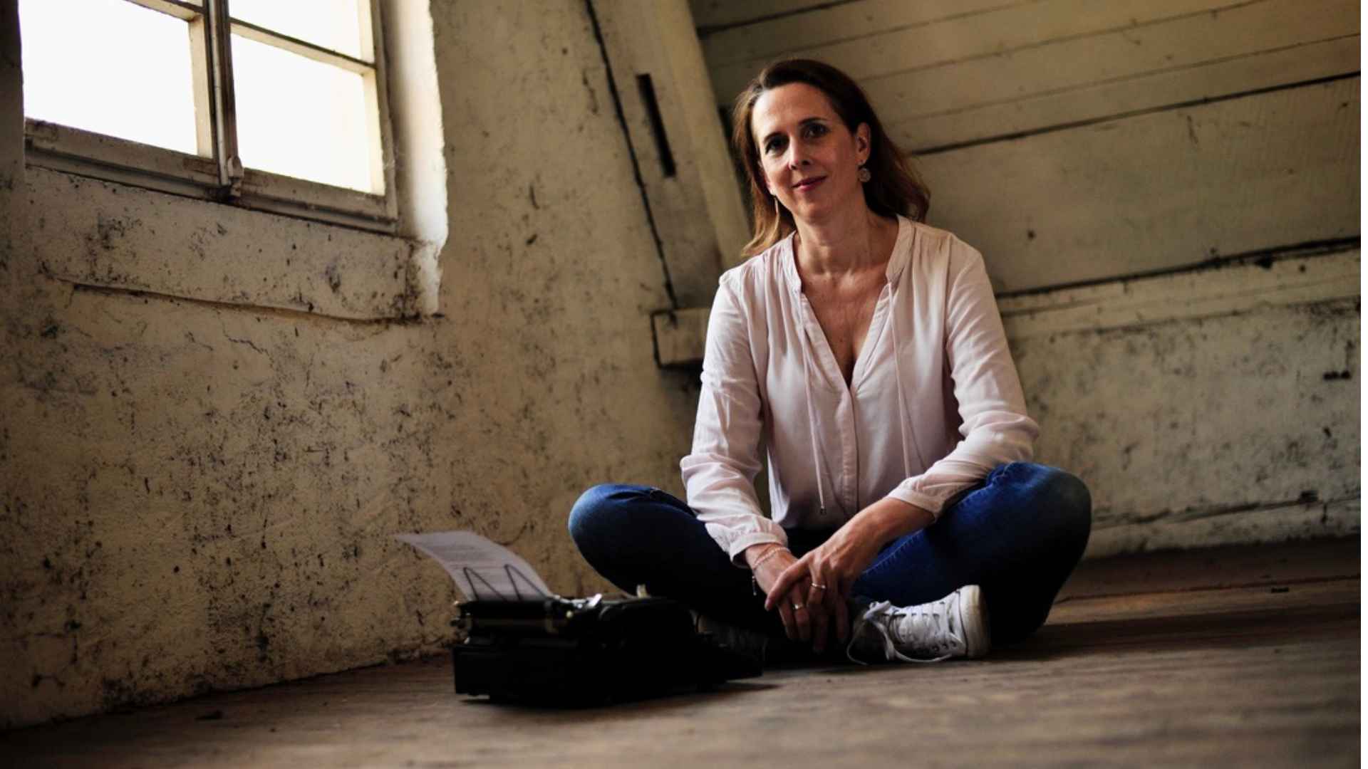 Die Lektorin Christine Storck sitzt im Schneidersitz vor einer Schreibmaschine