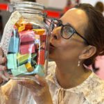 Lektorin Christine Storck hebt ein gefülltes Wünscheglas hoch und küsst es