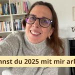 Lektorin Christine Storck steht vor einem Bücherregal und lacht in die Kamera