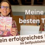 Lektorin Christine Storck, die als Anna Carlé Wohlfühlromane mit Sehnsuchtsorten schreibt, steht lachend in der Garage und zeigt ihr neues Buch.