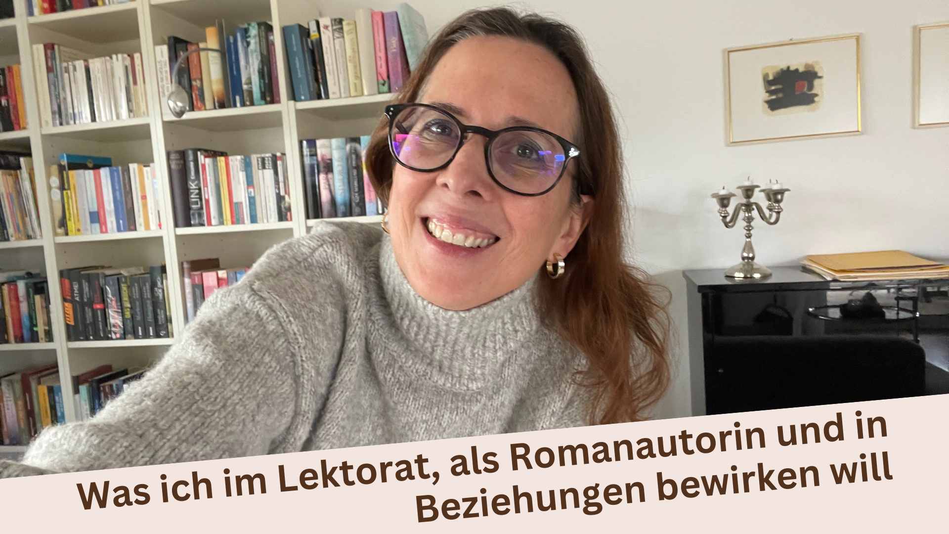 Lektorin Christine Storck steht vor ihrem Bücherregal im Wohnzimmer und lacht in die Kamera