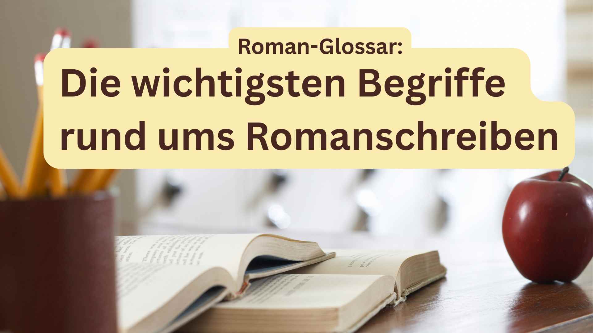 Auf dem Bild sind zwei aufgeschlagene Bücher auf einem Schreibtisch zu sehen. Daneben steht ein Becher mit Bleistiften, auf der anderen Seite liegt ein Apfel
