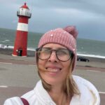 Lektorin Christine Storck steht vor dem Leuchtturm in Westkapelle am Strand