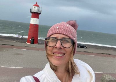 Lektorin Christine Storck steht vor dem Leuchtturm in Westkapelle am Strand