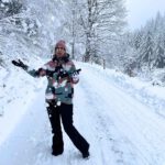 Lektorin Christine Storck fängt auf einem verschneiten Weg im Schwarzwald Schnee auf, der vom Baum fällt.