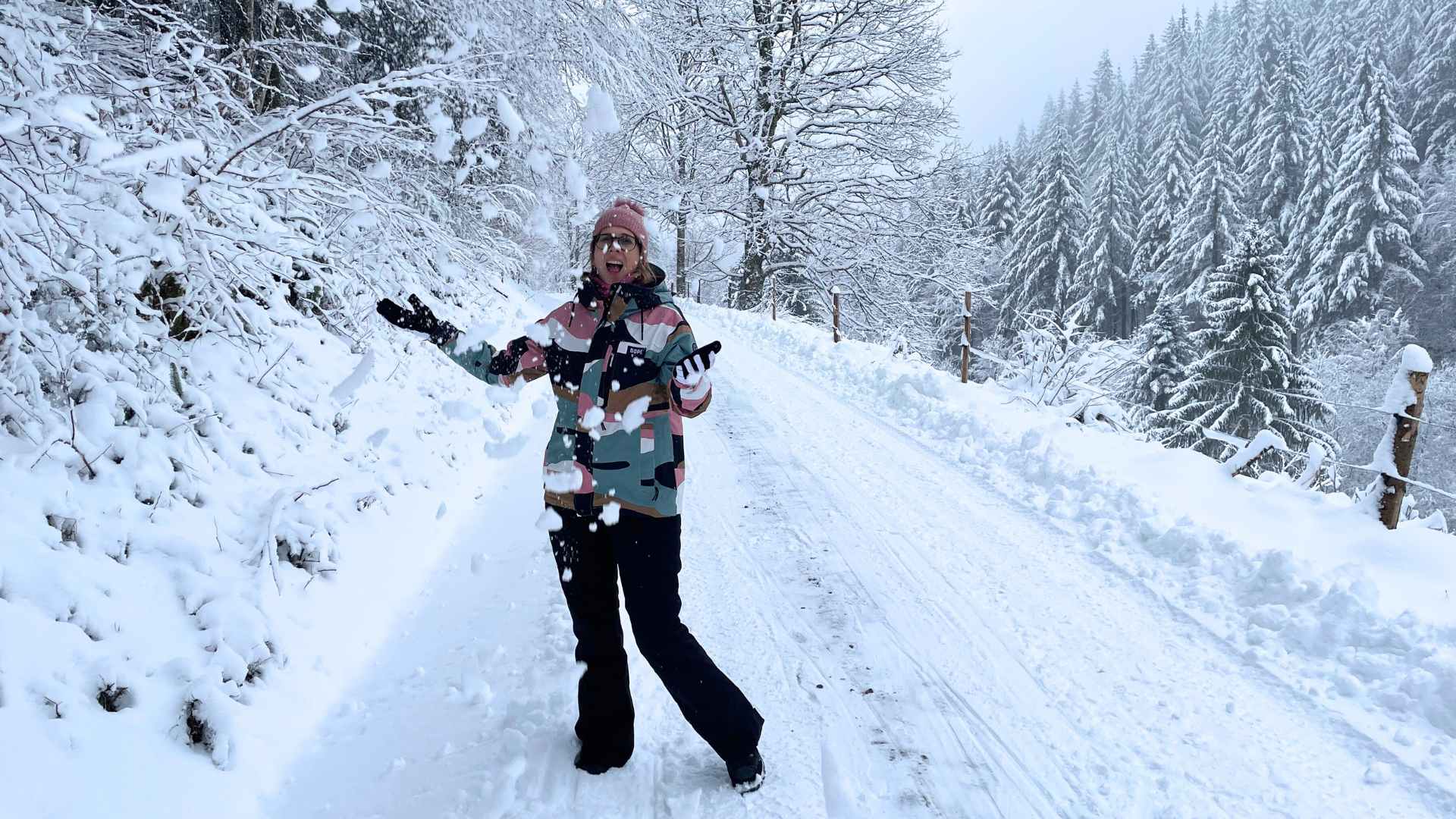 Lektorin Christine Storck fängt auf einem verschneiten Weg im Schwarzwald Schnee auf, der vom Baum fällt.