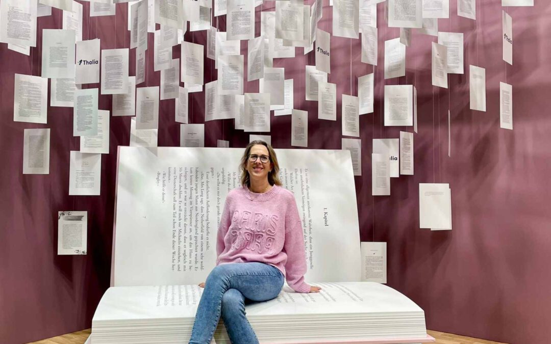 Lektorin Christine Storck sitzt auf der Frankfurter Buchmesse auf einem riesigen Buch-Sessel