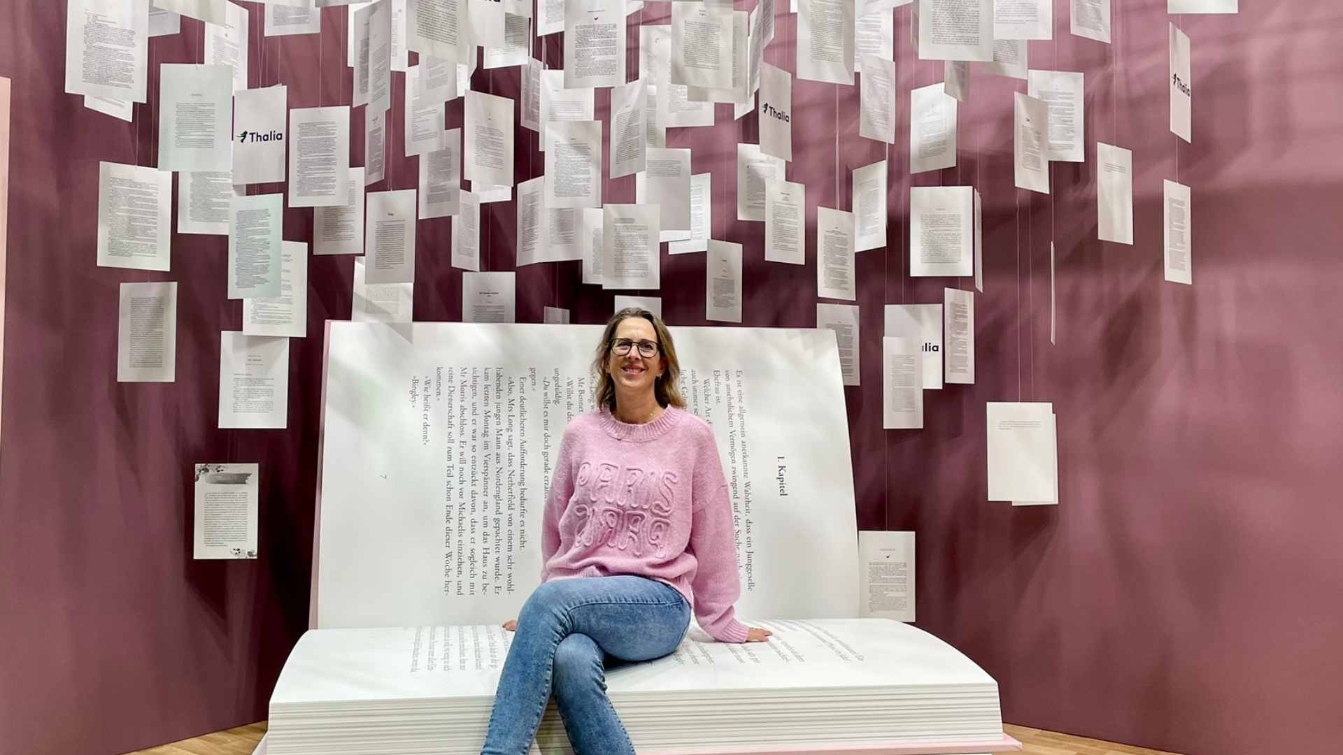 Lektorin Christine Storck sitzt auf der Frankfurter Buchmesse auf einem riesigen Buch-Sessel