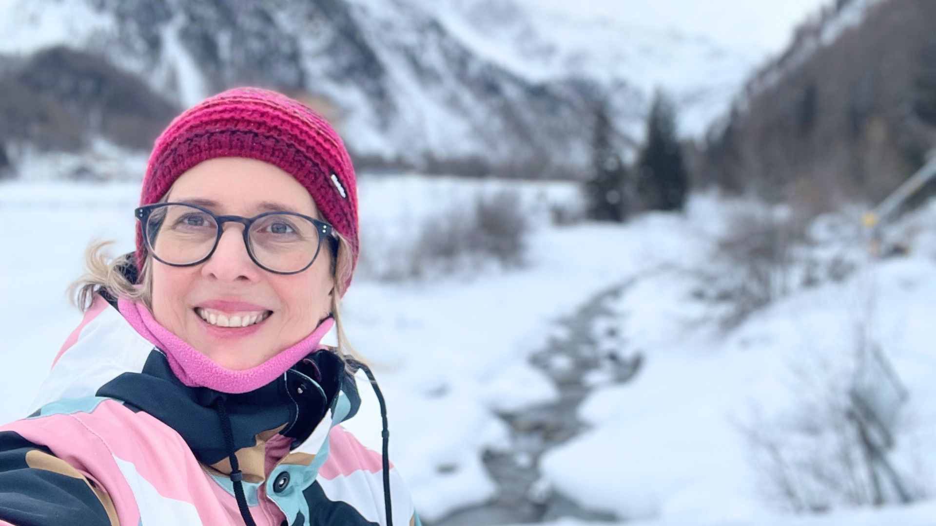 Lektorin Christine Storck lacht bei einem Schneespaziergang in Sulden/Südtirol in die Kamera.