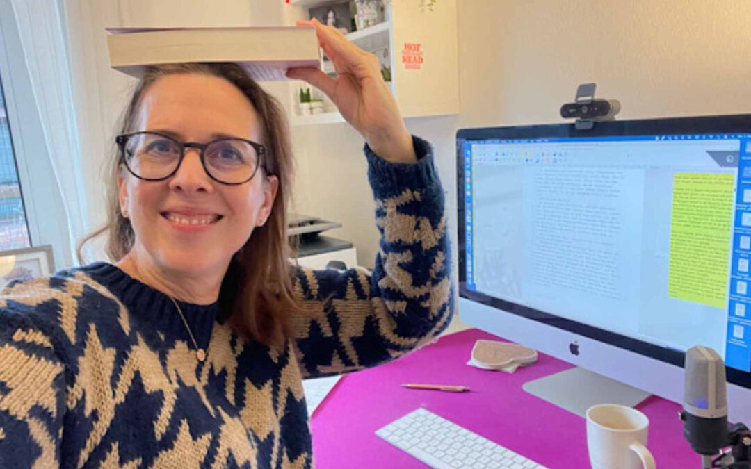 Lektorin Christine Storck sitzt in ihrem Büro am Schreibtisch und jongliert ein Buch auf ihrem Kopf