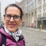 Lektorin Christine Storck steht morgens in der Leipziger Altstadt und lacht in die Kamera