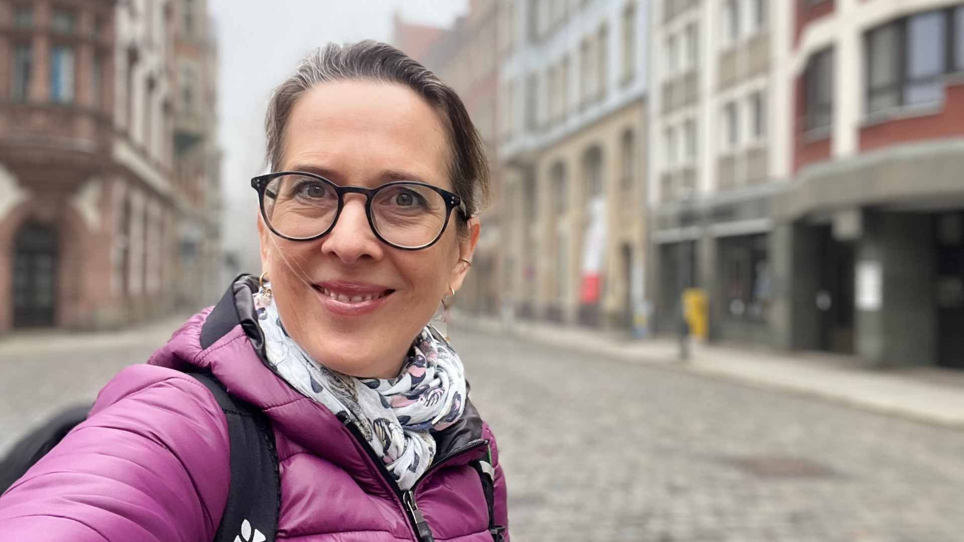 Lektorin Christine Storck steht morgens in der Leipziger Altstadt und lacht in die Kamera