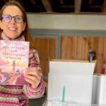 Lektorin und Romanautorin Christine Storck hält ihr frisch eingetroffenes Buch in die Kamera