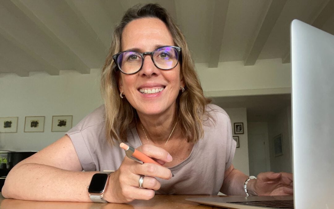 Lektorin Christine Storck sitzt an ihrem Laptop und lacht in die Kamera