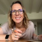 Lektorin Christine Storck sitzt an ihrem Laptop und lacht in die Kamera